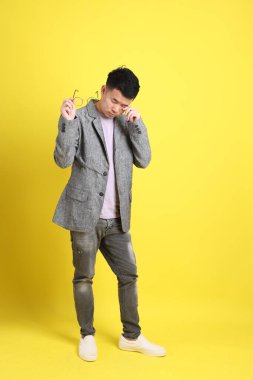 Sarı arka planda gri ceketli Asyalı LGBTQ adamı..