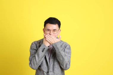 Sarı arka planda gri ceketli Asyalı LGBTQ adamı..