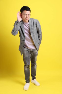 Sarı arka planda gri ceketli Asyalı LGBTQ adamı..