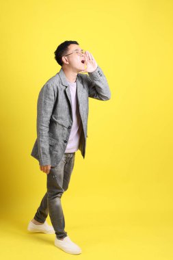 Sarı arka planda gri ceketli Asyalı LGBTQ adamı..