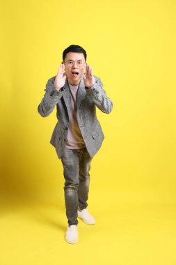 Sarı arka planda gri ceketli Asyalı LGBTQ adamı..