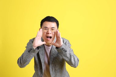 Sarı arka planda gri ceketli Asyalı LGBTQ adamı..