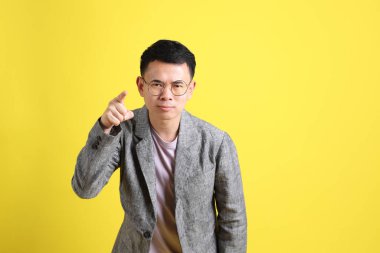 Sarı arka planda gri ceketli Asyalı LGBTQ adamı..