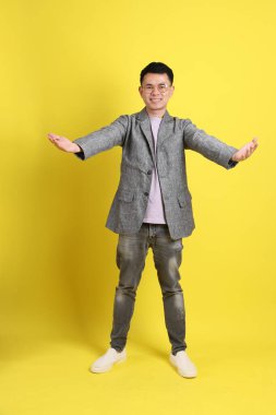 Sarı arka planda gri ceketli Asyalı LGBTQ adamı..