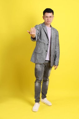 Sarı arka planda gri ceketli Asyalı LGBTQ adamı..