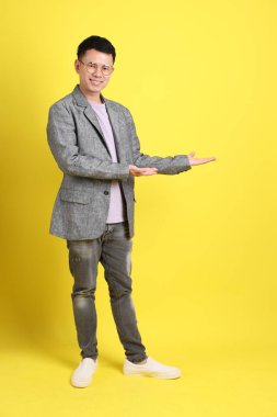 Sarı arka planda gri ceketli Asyalı LGBTQ adamı..