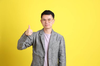 Sarı arka planda gri ceketli Asyalı LGBTQ adamı..