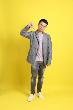 Sarı arka planda gri ceketli Asyalı LGBTQ adamı..