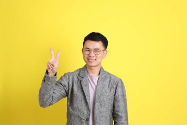 Sarı arka planda gri ceketli Asyalı LGBTQ adamı..