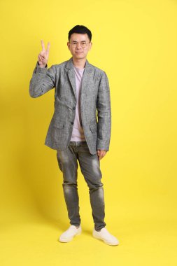 Sarı arka planda gri ceketli Asyalı LGBTQ adamı..