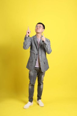 Sarı arka planda gri ceketli Asyalı LGBTQ adamı..