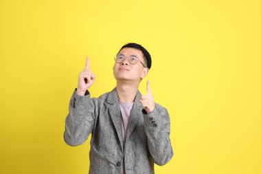 Sarı arka planda gri ceketli Asyalı LGBTQ adamı..