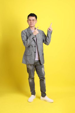 Sarı arka planda gri ceketli Asyalı LGBTQ adamı..