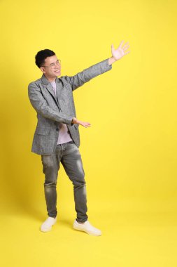 Sarı arka planda gri ceketli Asyalı LGBTQ adamı..