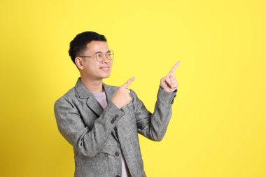 Sarı arka planda gri ceketli Asyalı LGBTQ adamı..