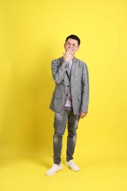 Sarı arka planda gri ceketli Asyalı LGBTQ adamı..