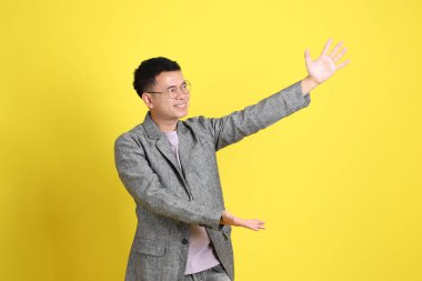 Sarı arka planda gri ceketli Asyalı LGBTQ adamı..