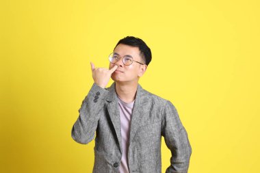 Sarı arka planda gri ceketli Asyalı LGBTQ adamı..