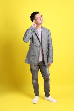 Sarı arka planda gri ceketli Asyalı LGBTQ adamı..