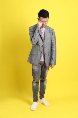 Sarı arka planda gri ceketli Asyalı LGBTQ adamı..