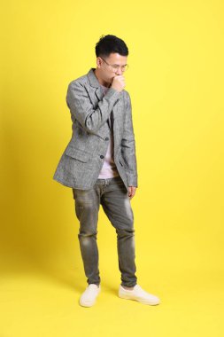 Sarı arka planda gri ceketli Asyalı LGBTQ adamı..