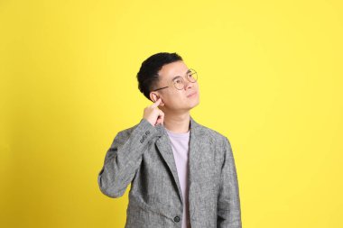 Sarı arka planda gri ceketli Asyalı LGBTQ adamı..