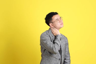 Sarı arka planda gri ceketli Asyalı LGBTQ adamı..