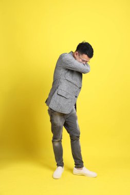 Sarı arka planda gri ceketli Asyalı LGBTQ adamı..