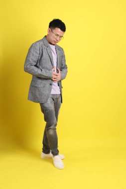 Sarı arka planda gri ceketli Asyalı LGBTQ adamı..