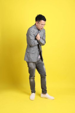 Sarı arka planda gri ceketli Asyalı LGBTQ adamı..