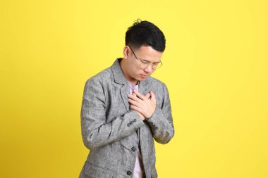 Sarı arka planda gri ceketli Asyalı LGBTQ adamı..