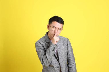 Sarı arka planda gri ceketli Asyalı LGBTQ adamı..