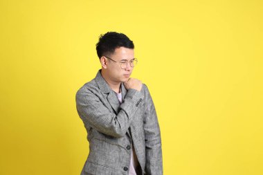 Sarı arka planda gri ceketli Asyalı LGBTQ adamı..