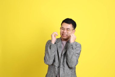 Sarı arka planda gri ceketli Asyalı LGBTQ adamı..