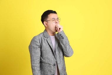 Sarı arka planda gri ceketli Asyalı LGBTQ adamı..