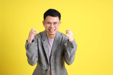 Sarı arka planda gri ceketli Asyalı LGBTQ adamı..