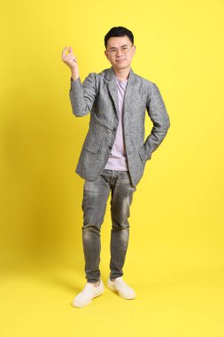 Sarı arka planda gri ceketli Asyalı LGBTQ adamı..