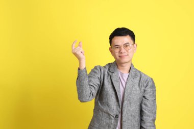 Sarı arka planda gri ceketli Asyalı LGBTQ adamı..