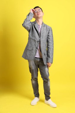 Sarı arka planda gri ceketli Asyalı LGBTQ adamı..