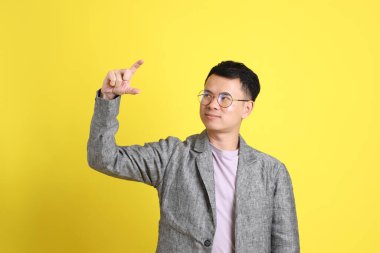 Sarı arka planda gri ceketli Asyalı LGBTQ adamı..