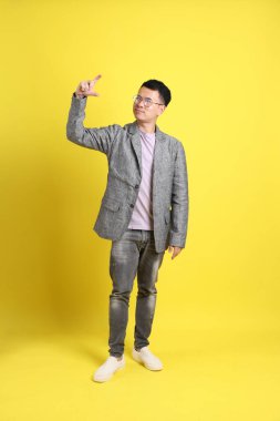 Sarı arka planda gri ceketli Asyalı LGBTQ adamı..