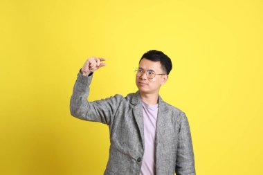 Sarı arka planda gri ceketli Asyalı LGBTQ adamı..