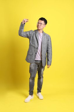 Sarı arka planda gri ceketli Asyalı LGBTQ adamı..