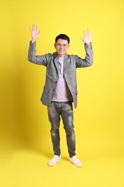 Sarı arka planda gri ceketli Asyalı LGBTQ adamı..