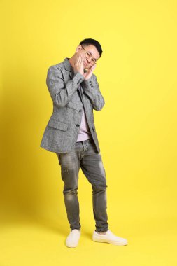 Sarı arka planda gri ceketli Asyalı LGBTQ adamı..