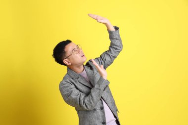 Sarı arka planda gri ceketli Asyalı LGBTQ adamı..