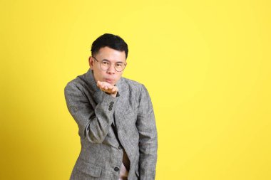 Sarı arka planda gri ceketli Asyalı LGBTQ adamı..