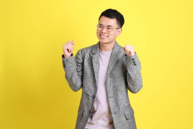 Sarı arka planda gri ceketli Asyalı LGBTQ adamı..