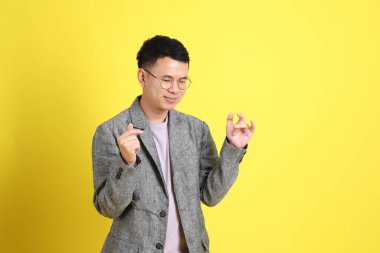 Sarı arka planda gri ceketli Asyalı LGBTQ adamı..