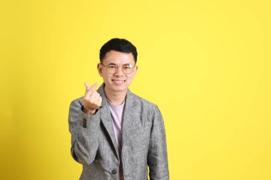 Sarı arka planda gri ceketli Asyalı LGBTQ adamı..